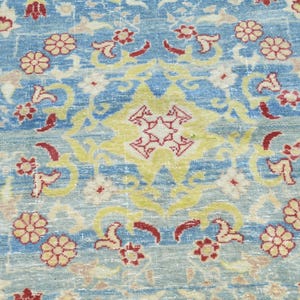 May include: A blue rug with a floral pattern in shades of red, yellow, and white. The rug has a central medallion with a starburst design.
