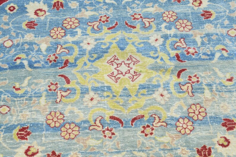 May include: A blue rug with a floral pattern in shades of red, yellow, and white. The rug has a central medallion with a starburst design.