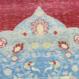 May include: A vintage rug with a red center and a blue and white floral pattern. The rug has a traditional design with a central medallion and a border.