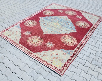May include: A vintage red rug with a cream-colored border and intricate floral patterns in shades of cream, yellow, and blue.