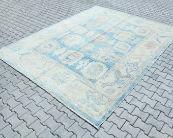 Könnte beinhalten: Ein Vintage-Teppich in Blau- und Cremetönen. Der Teppich hat ein Blumenmuster und einen Rand mit geometrischem Design.
