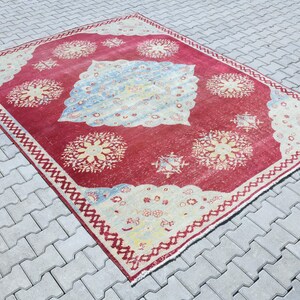 May include: A vintage red and cream rug with a floral pattern. The rug has a faded look and is worn in some areas.