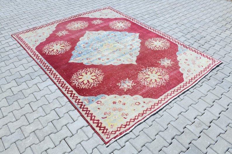 May include: A vintage red and cream rug with a floral pattern. The rug has a faded look and is worn in some areas.