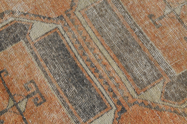 K&ouml;nnte beinhalten: Nahaufnahme eines Vintage-Teppichs mit einem geometrischen Muster in Braun-, Beige- und Oranget&ouml;nen.