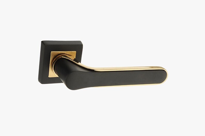 Op de afbeelding: Zwarte deurknop met een gouden rand. De knop is vierkant met een afgeronde hendel.
