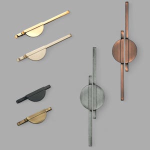 Puede incluir: Cuatro tiradores de armario diferentes en varios acabados. Dos tienen forma de semicírculo con la parte posterior plana. Dos son verticales con un centro redondo y la parte posterior plana.