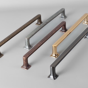 Puede incluir: Cuatro tiradores de armario de metal en varios acabados: latón antiguo, níquel cepillado, bronce frotado con aceite y negro. Cada tirador mide aproximadamente 25 cm de largo.