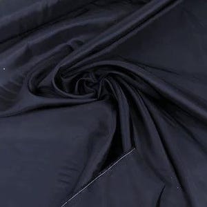 May include: A close-up of a dark blue fabric with a smooth, silky texture. The fabric is folded and draped, showcasing its flowing nature.
