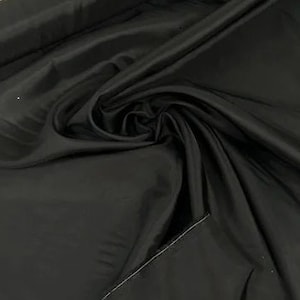 May include: Black fabric with a smooth, silky texture. The fabric is folded and draped, showing its drape and flow.