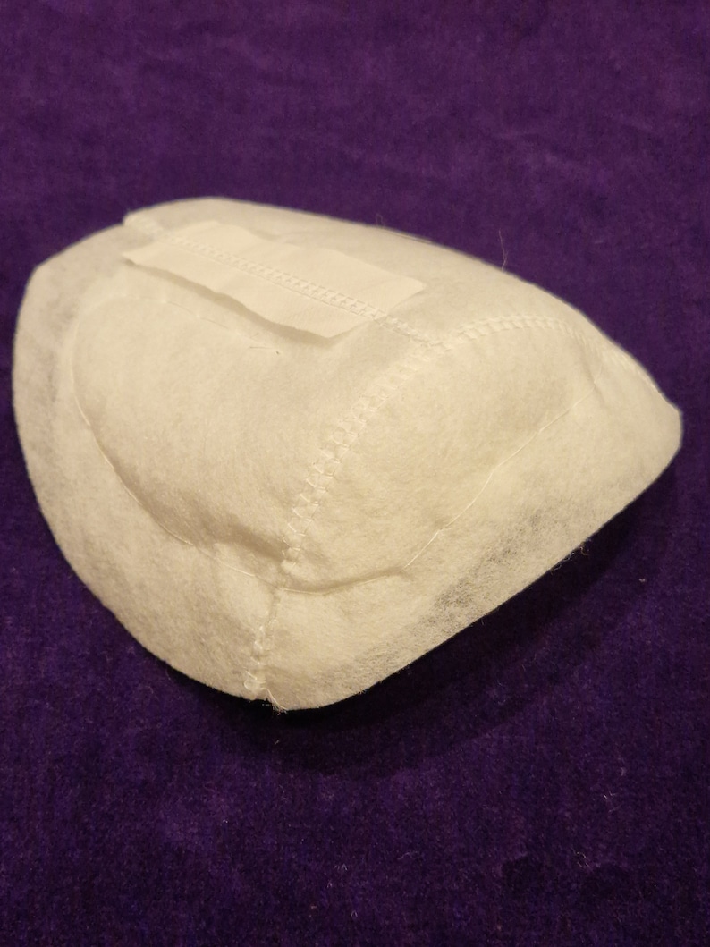 May include: White fabric filter with a sewn seam around the edge. The filter has a white label with a zig-zag stitch on the top.