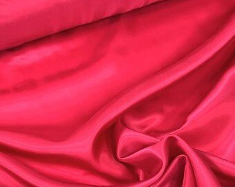 May include: A close-up of a bright red satin fabric. The fabric is smooth and silky, with a slight sheen. It is folded in a way that shows off its texture and drape.