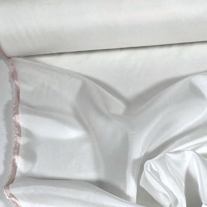 May include: White silk fabric with a pink edge. The fabric is smooth and has a slight sheen.
