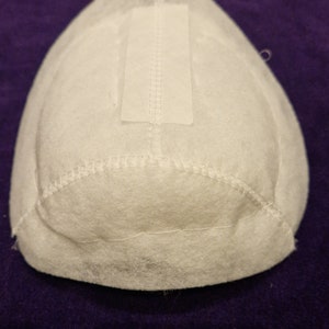 May include: White fabric filter with a white rectangular patch sewn on top. The filter is shaped like a dome and has a stitched edge.