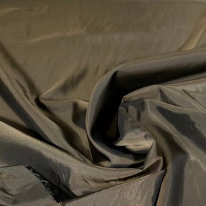 May include: A close-up of a smooth, dark brown fabric with a silky sheen. The fabric is folded and draped, showcasing its texture and drape.
