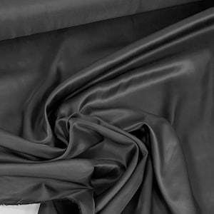 May include: A smooth, black fabric with a silky texture. The fabric is draped and folded, showcasing its luxurious feel.