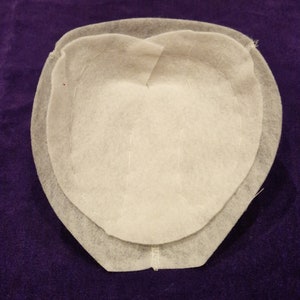 May include: A white felt hat crown with a double layer of fabric and visible stitching.
