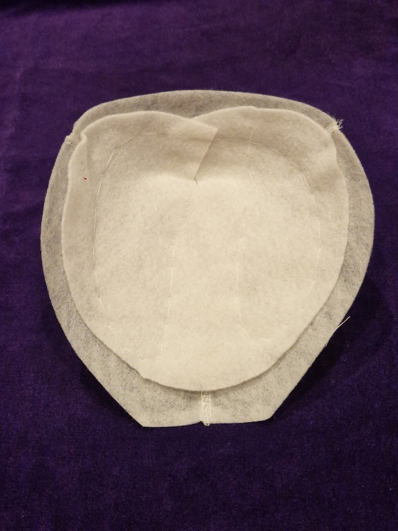 May include: A white felt hat crown with a double layer of fabric and visible stitching.