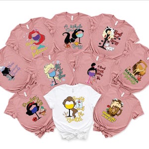 May include: Ten pink t-shirts with different Disney character designs and sayings. Each shirt features a character holding a glass of wine or a beer mug. The sayings include "A Whole New Wine", "Drink Like a Beast", "Hakuna Matata", "Under the Influence", "Beauty and the Bottle", "A Deal With a Witch for Wine", "Pouring Drinks", "Bottoms Up", "Let It Go", and "Just the Tip".