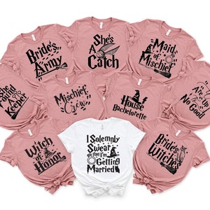 May include: A set of nine pink t-shirts with various Harry Potter themed phrases and graphics. The shirts feature phrases like "Bride's Army", "She's a Catch", "Maid of Mischief", "Mischief Crew", "House Bachelorette", "She Found a Keeper", "Witch of Honor", "Are Up to No Good", and "Bride's Witches". One white t-shirt features the phrase "I Solemnly Swear that I'm Getting Married" with a graphic of a witch's hat.