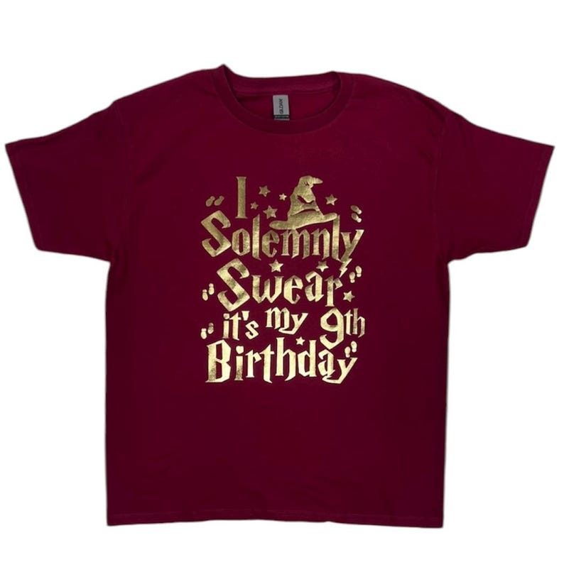 May include: Burgundy t-shirt with a gold graphic that says "I solemnly swear it's my 9th birthday" with a wizard hat graphic.