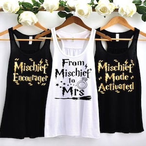 May include: Three black tank tops with gold lettering. The tank tops have different sayings: "Mischief Encourager", "From Mischief to Mrs." and "Mischief Mode Activated".