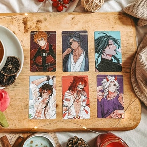 Puede incluir: Seis tarjetas coloridas con ilustraciones de personajes de anime. Los personajes están dibujados en un estilo estilizado, inspirado en el manga. Las tarjetas están impresas sobre un fondo blanco.