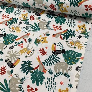 May include: White fabric with a repeating pattern of jungle animals and plants. The animals include sloths, toucans, monkeys, and tigers. The plants are green and yellow and have a tropical feel.
