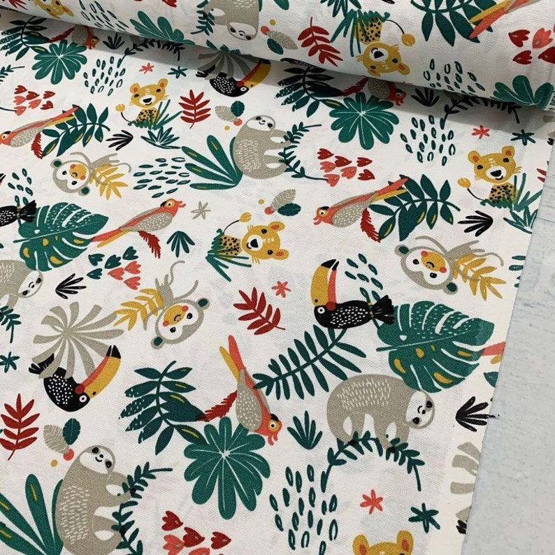 May include: White fabric with a repeating pattern of jungle animals and plants. The animals include sloths, toucans, monkeys, and tigers. The plants are green and yellow and have a tropical feel.