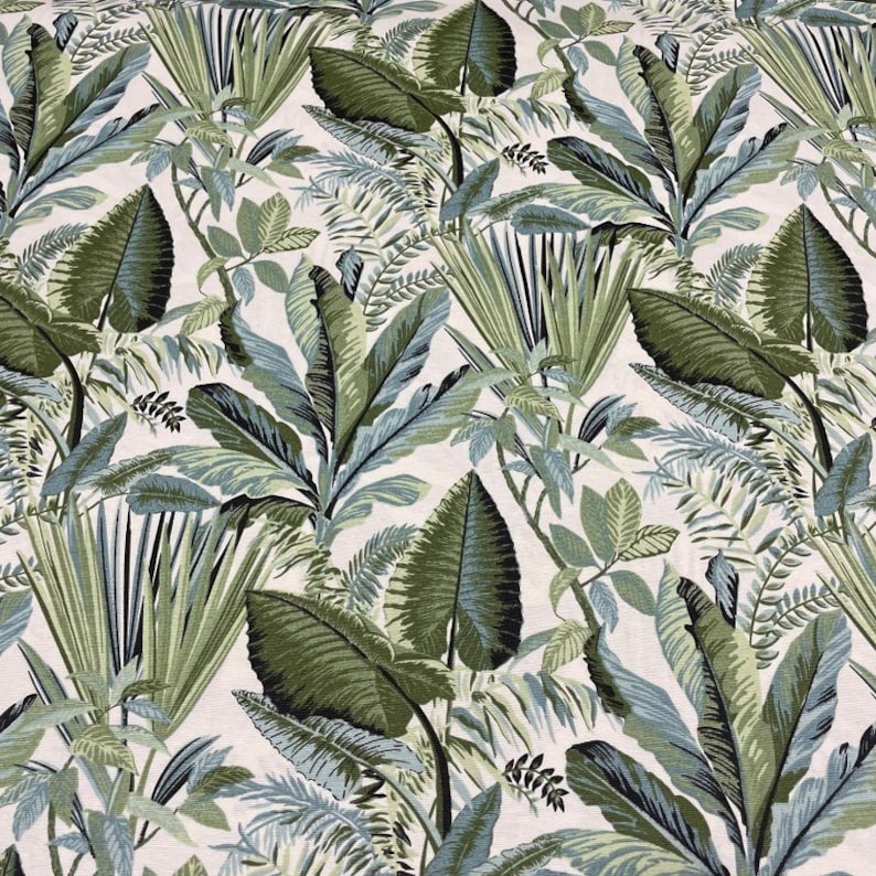 May include: A fabric featuring a tropical leaf design. The pattern showcases large, detailed leaves in shades of green and blue set against a cream background. The leaves vary in size and shape, creating a dense, jungle-like effect.