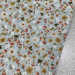 May include: A light blue fabric with a small floral pattern. The flowers are in shades of pink, yellow, and brown.