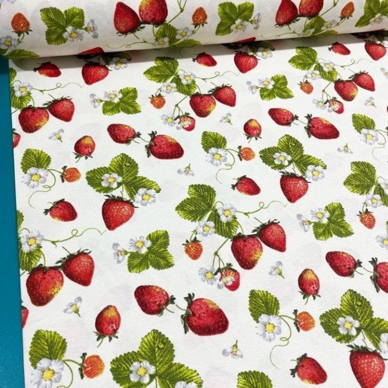 May include: White fabric with a repeating pattern of red strawberries and green leaves. The strawberries are arranged in a random pattern and are surrounded by small white flowers.