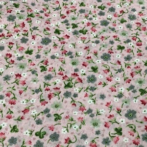 May include: A pink fabric with a repeating pattern of small white, pink, and gray flowers. The fabric has a subtle texture.