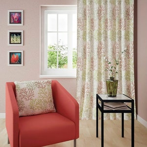 Puede incluir: Un sill&oacute;n rojo con un coj&iacute;n de estampado de coral se encuentra en una sala de estar con una mesa auxiliar y una ventana con vistas a los &aacute;rboles. La habitaci&oacute;n tiene paredes rosas y una cortina con estampado de coral.
