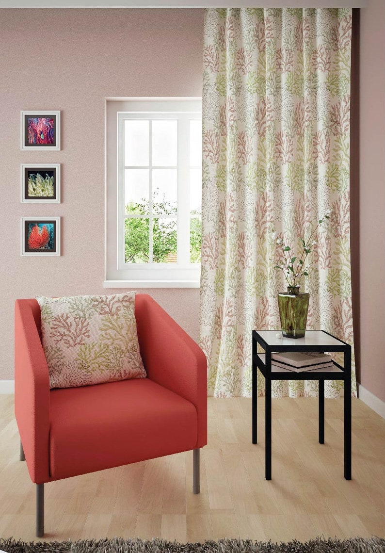 Puede incluir: Un sill&oacute;n rojo con un coj&iacute;n de estampado de coral se encuentra en una sala de estar con una mesa auxiliar y una ventana con vistas a los &aacute;rboles. La habitaci&oacute;n tiene paredes rosas y una cortina con estampado de coral.