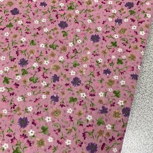 May include: Pink fabric with a small floral print in shades of white, purple, and green.