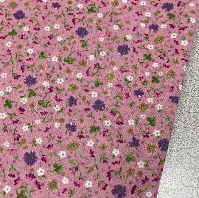 May include: Pink fabric with a small floral print in shades of white, purple, and green.