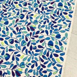 Op de afbeelding: Witte stof met een blauw en groen bloemenpatroon. Het patroon bevat kleine bladeren en bloemen in tinten blauw en groen.