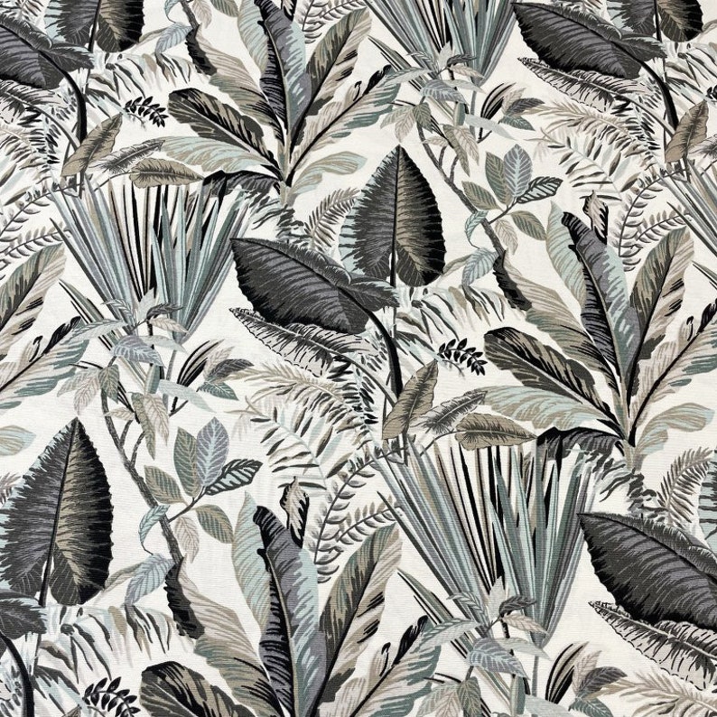 May include: A fabric featuring a tropical leaf design. The pattern showcases large, stylized leaves in shades of grey, black, and muted green against a white backdrop. The leaves vary in size and shape, creating a dense, jungle-like effect.
