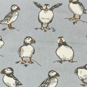 Peut inclure: Un motif r&eacute;p&eacute;t&eacute; de macareux sur un fond bleu clair. Les macareux sont blancs avec des marques noires et des becs orange. Certains macareux sont debout avec leurs ailes d&eacute;ploy&eacute;es, tandis que d'autres sont debout avec leurs ailes repli&eacute;es.