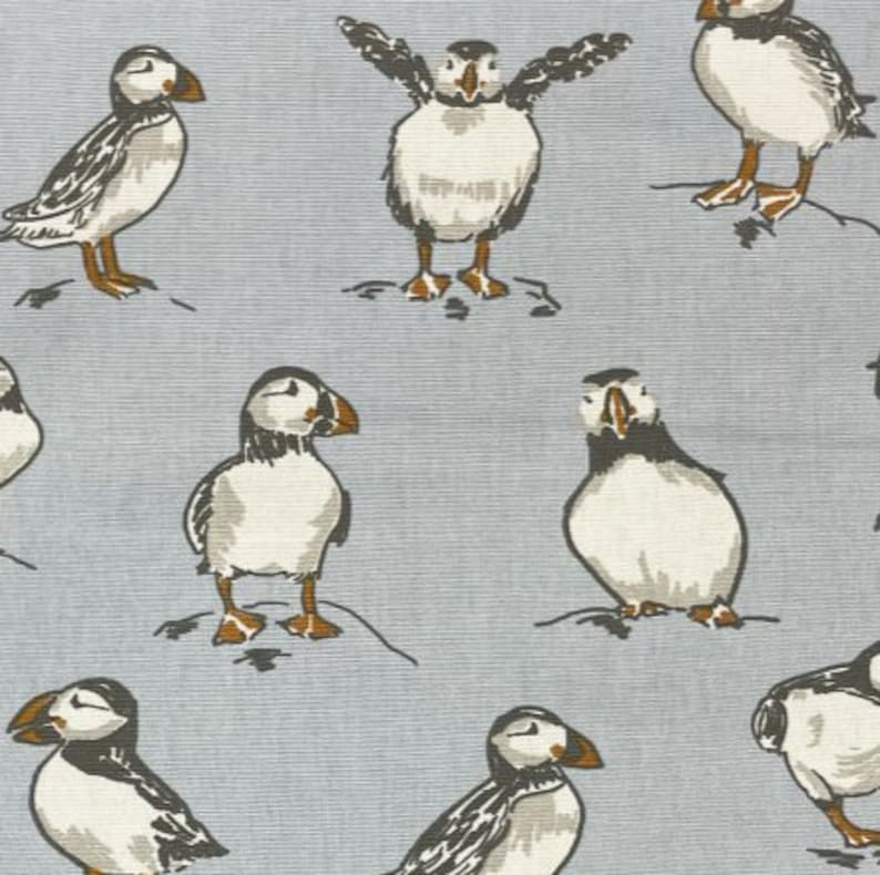 Peut inclure: Un motif r&eacute;p&eacute;t&eacute; de macareux sur un fond bleu clair. Les macareux sont blancs avec des marques noires et des becs orange. Certains macareux sont debout avec leurs ailes d&eacute;ploy&eacute;es, tandis que d'autres sont debout avec leurs ailes repli&eacute;es.
