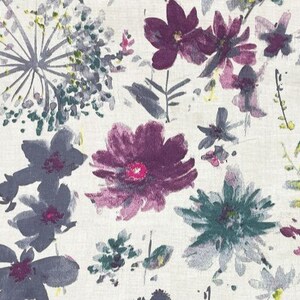 Puede incluir: Tela con estampado floral que presenta flores estilo acuarela en tonos morados, grises y verdes sobre un fondo crema. El dise&ntilde;o incluye varias formas y tama&ntilde;os de flores, creando una est&eacute;tica natural y art&iacute;stica.
