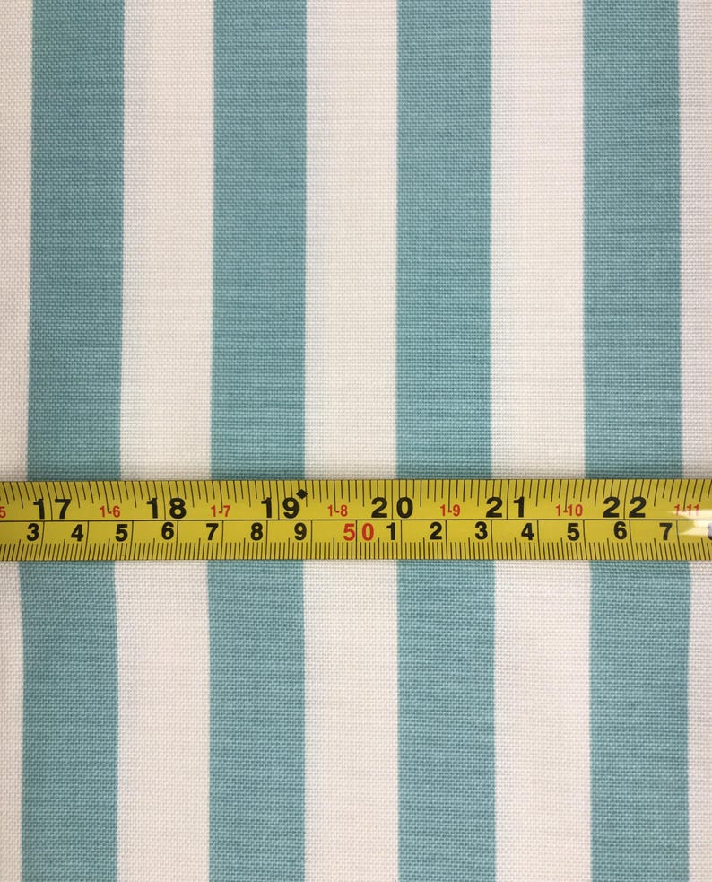 May include: A close-up of white and teal striped fabric with a yellow measuring tape across the bottom. The tape reads "17 18 19 20 21 22".