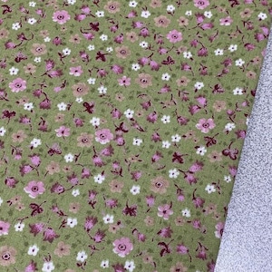 May include: A green fabric with a small pink and white floral pattern. The fabric is soft and has a subtle sheen.