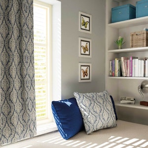 May include: A window seat with a blue and white patterned curtain, two pillows, and a bookshelf with books and decorative items. The wall is painted a light gray color and there are three framed pictures of butterflies.