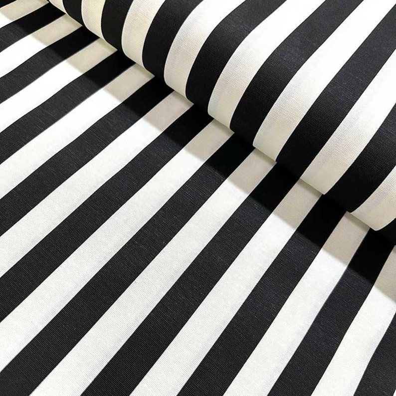 May include: Black and white striped fabric. The fabric is folded in half, showing the stripes running diagonally.