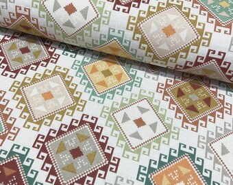 May include: Close-up of a fabric roll featuring a repeating geometric pattern. The design includes diamond shapes with triangles and squares in shades of brown, green, and orange, set against a white background.