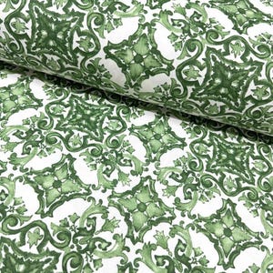 May include: White fabric with a repeating pattern of green stylized floral designs. The pattern resembles a traditional tile design.
