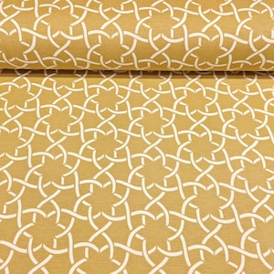 May include: Mustard yellow fabric with a repeating white geometric pattern. The design features interwoven lines creating a star-like motif. The fabric is folded, showing the texture and detail of the material.