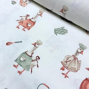 May include: White fabric with a repeating pattern of geese wearing chef hats and aprons. The geese are holding kitchen utensils and there are other kitchen-themed illustrations like a pot and a spoon.