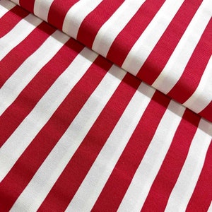 May include: Red and white striped fabric with a smooth texture. The fabric is folded in half, showing the stripes running vertically.